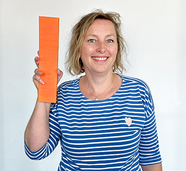 Person mit einem gebastelten Buchstaben I aus Pappe in einer Hand.